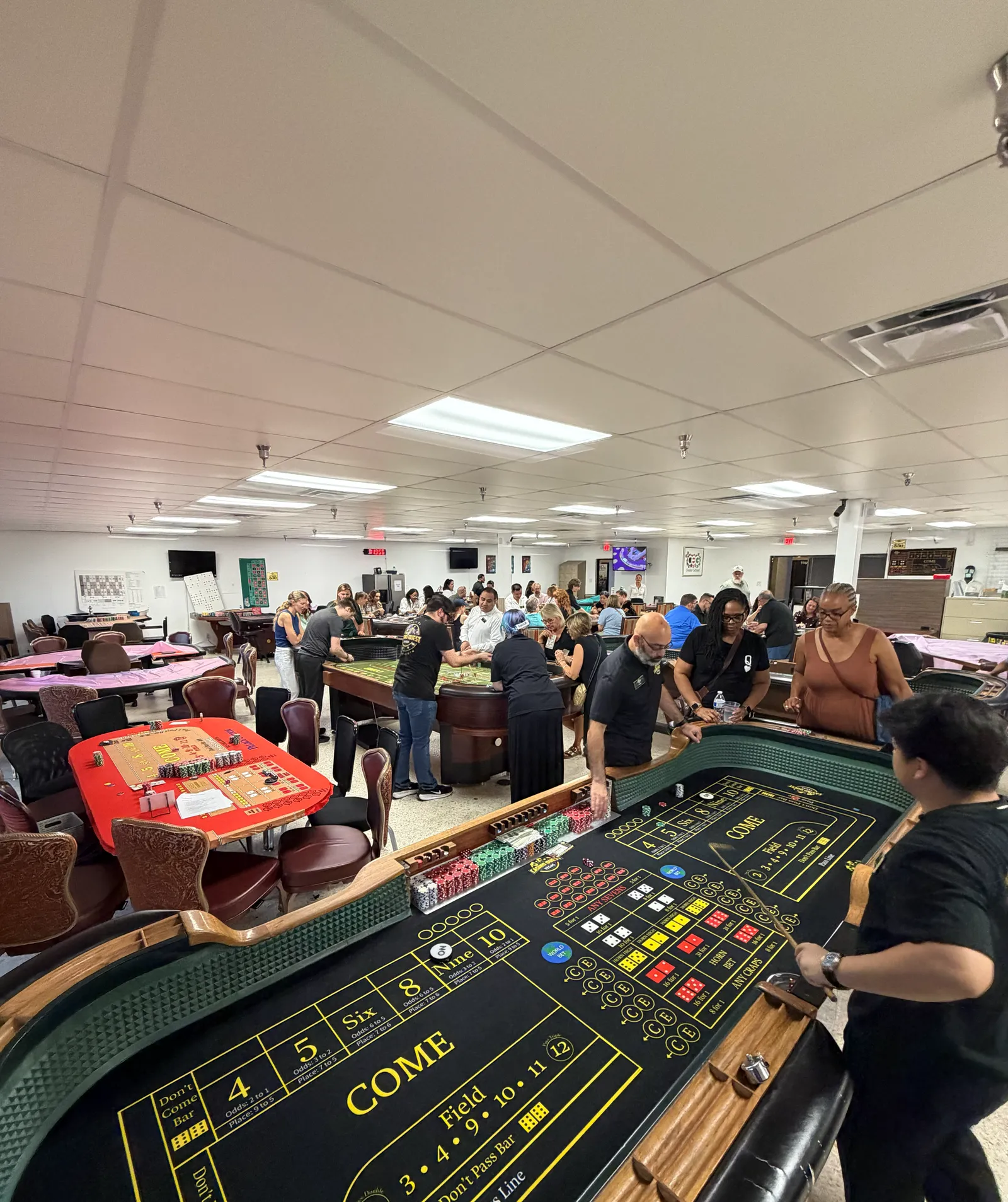 Busy casino training room with multiple tables and a group learning craps in Las Vegas
