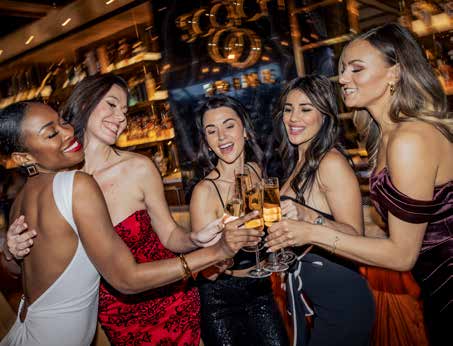 Five women toasting with champagne flutes at the bar