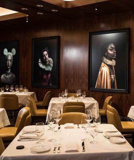 Dining room lined with large framed portrait photography on walnut walls