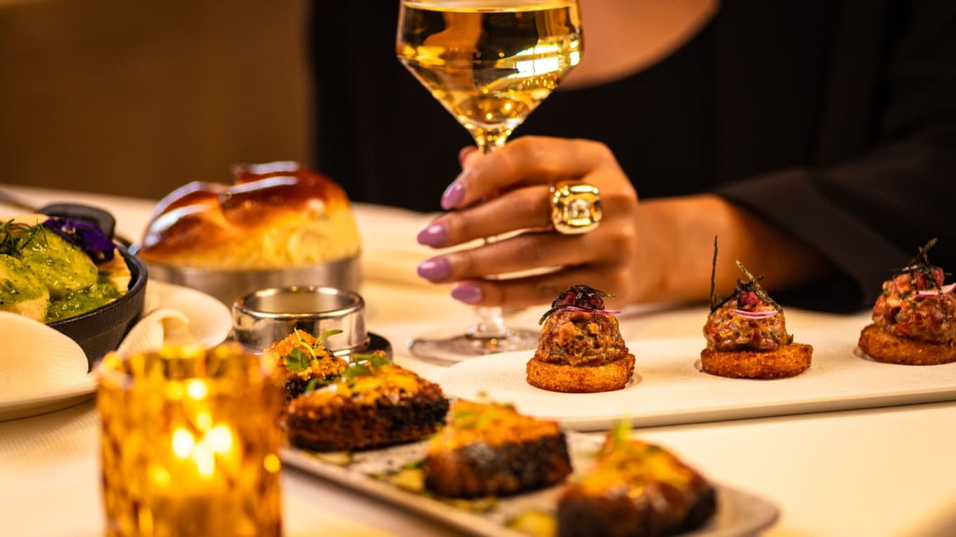 Tartare bites, seared appetizers and a glass of white wine by candlelight