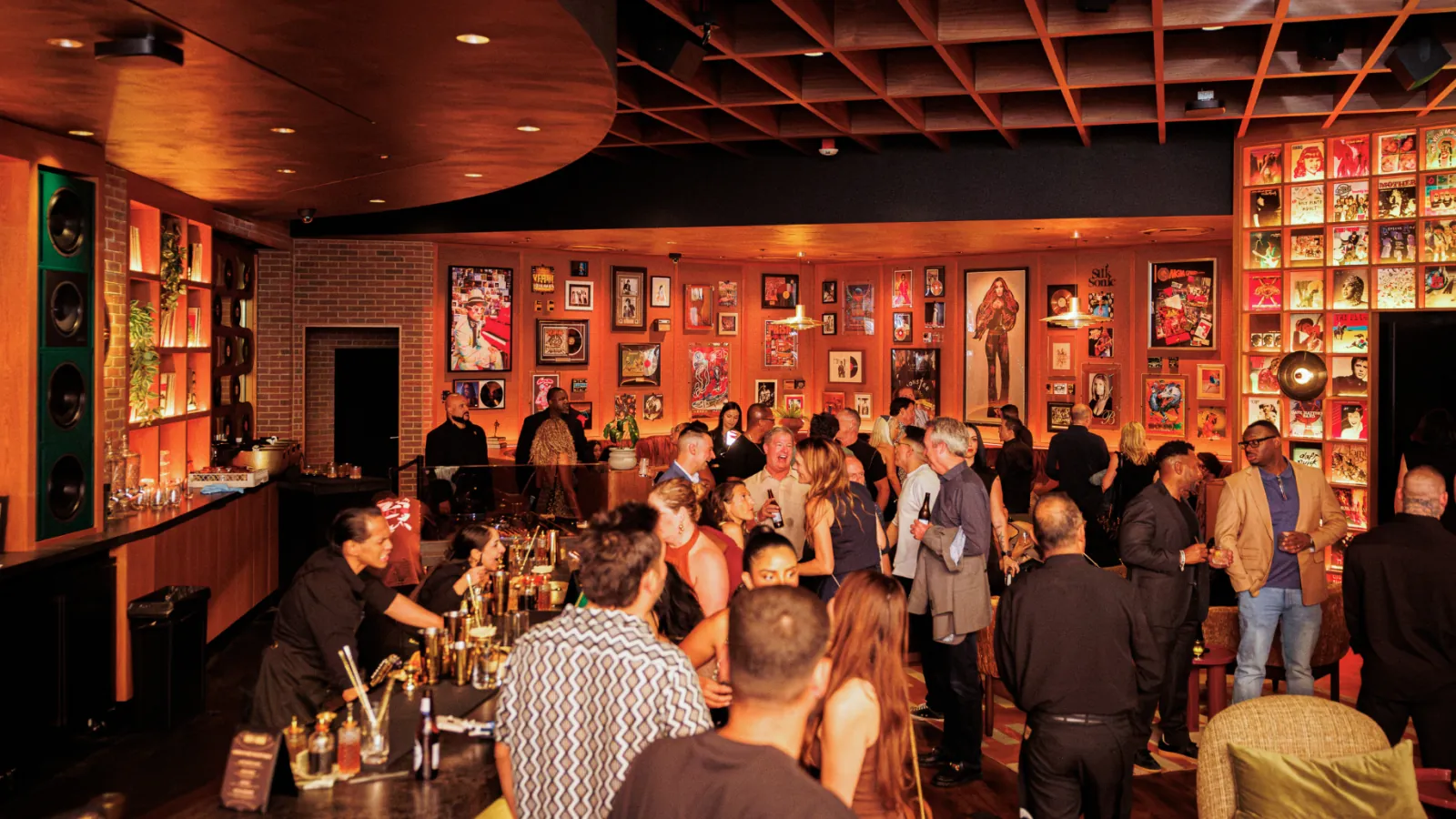 Guests in the Vinyl Room lounge at Mandalay Bay under a lit wall of framed albums